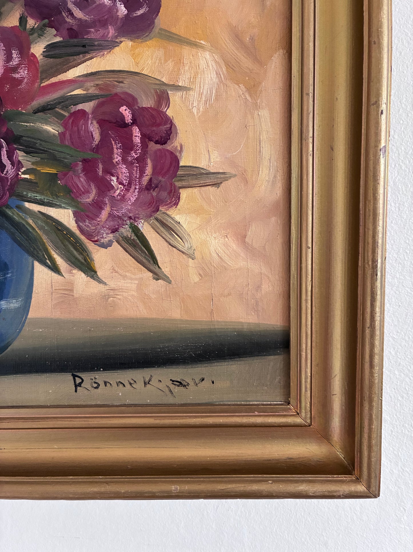 Floral painting with a gold frame on a white wall