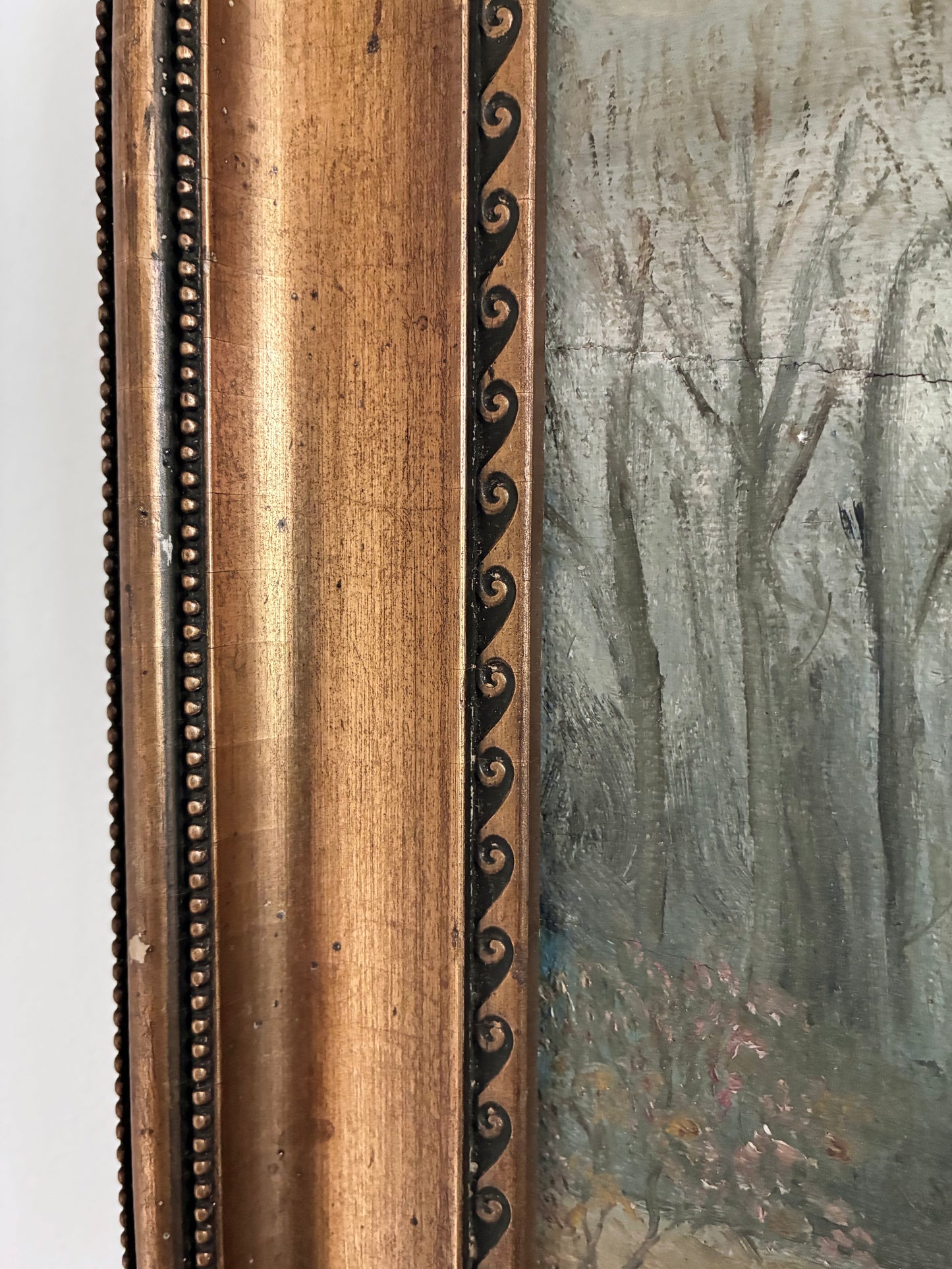 Close-up of a antique painting with a detailed wooden gold frame.