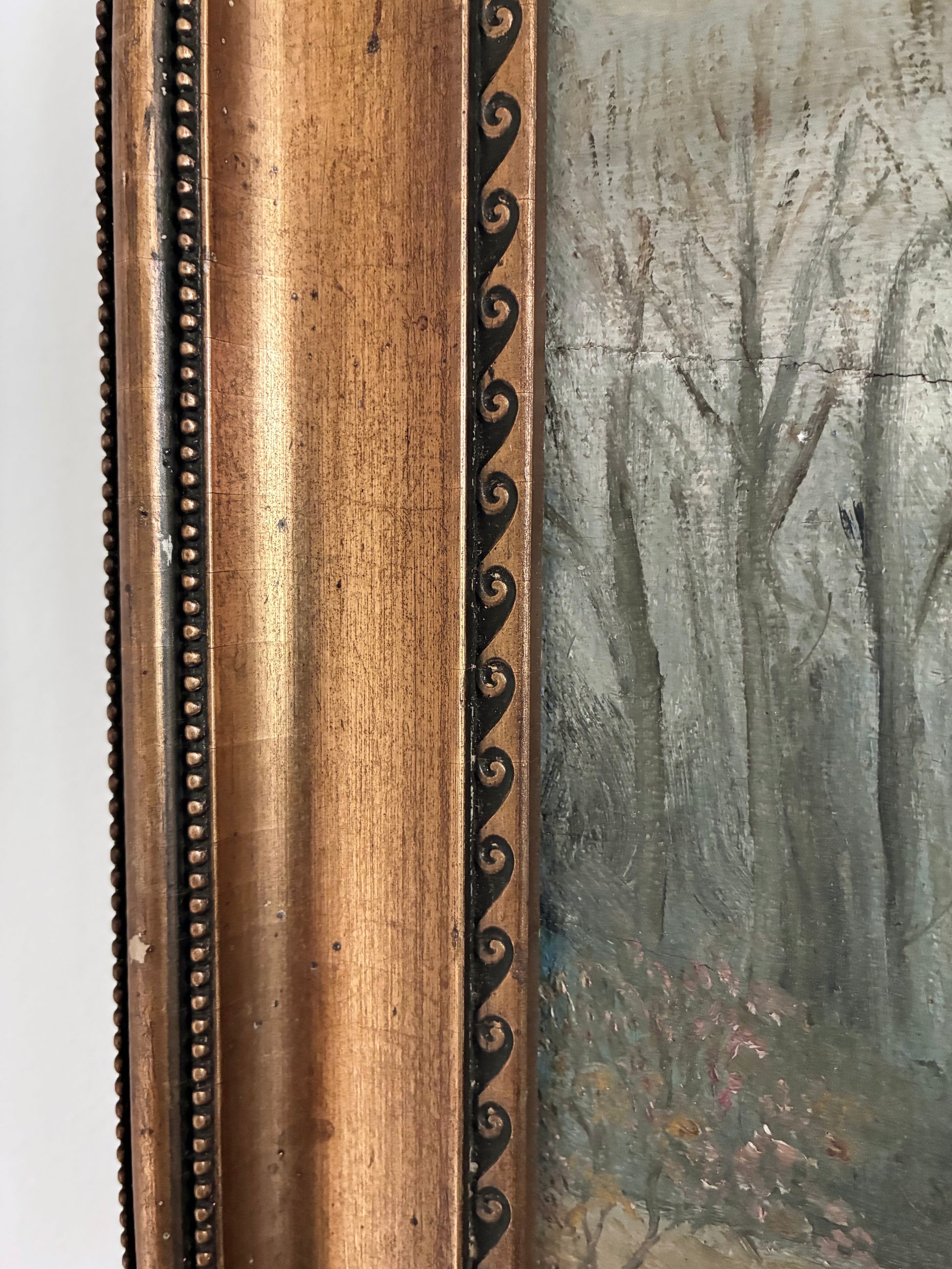Close-up of a antique painting with a detailed wooden gold frame.