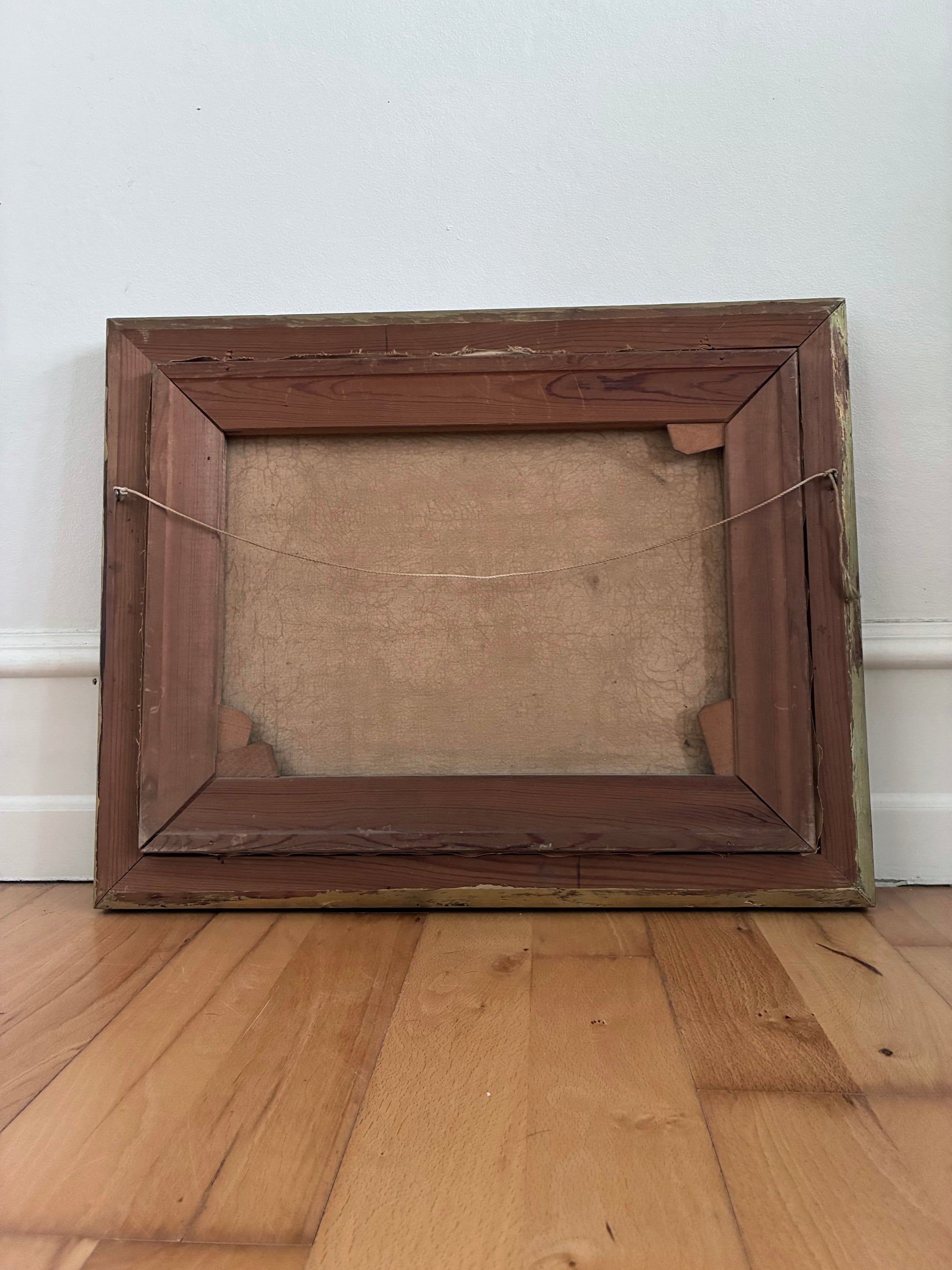 Wooden picture frame on a wooden floor with a white wall background