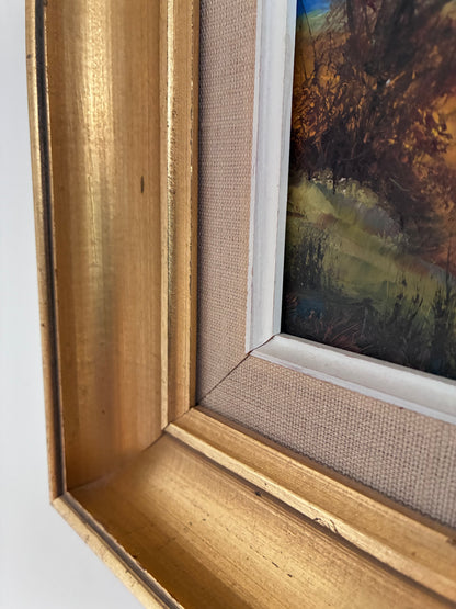 Close-up of a gold-framed painting with a textured linen mat.